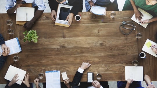 business people and doctora around a table, communicating