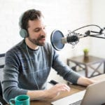 man recording podcast at laptop