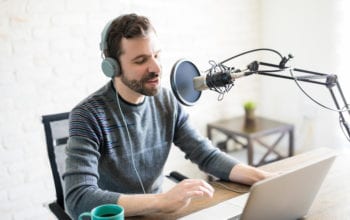 man recording podcast at laptop