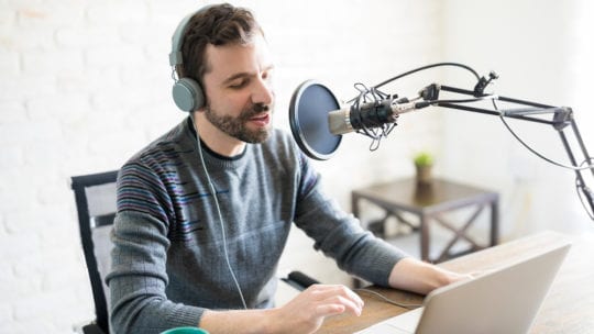 man recording podcast at laptop