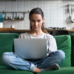 women on laptop on green couch