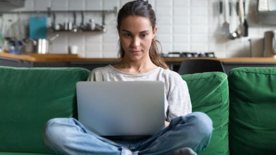 women on laptop on green couch