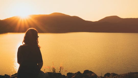 woman watching sunset by lake