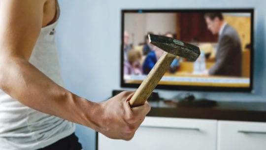 man with hammer watching the news