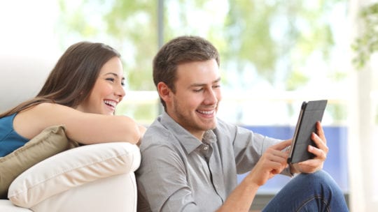 couple laughing at tablet