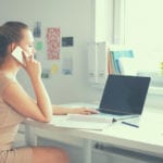 girl on phone working at laptop