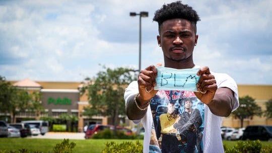 Quinton Desamours, former Publix employee, holds BLM mask in front of supermarket