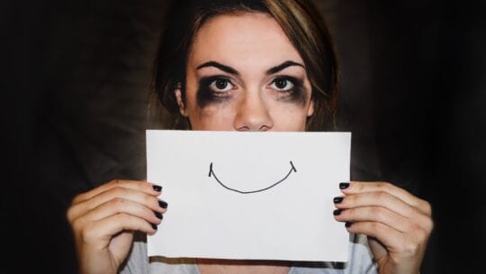 stress, woman crying but pretending to smile