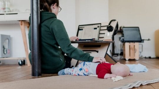 working mom on laptop with baby sleeping