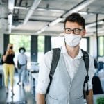 man in mask walking into office