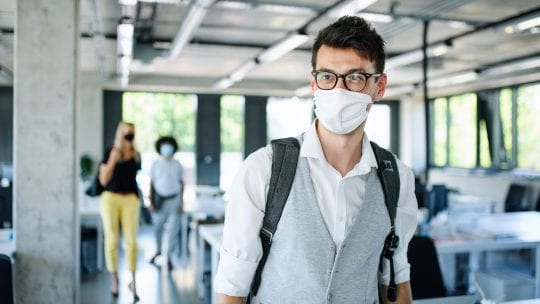 man in mask walking into office