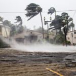 hurricane hitting building, flooding and trees blown aside