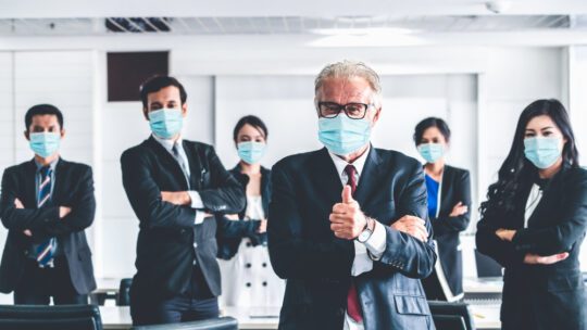 Masked employees in suits give thumbs up