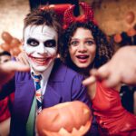 man in joker costume, woman in devil costume, smiling at camera