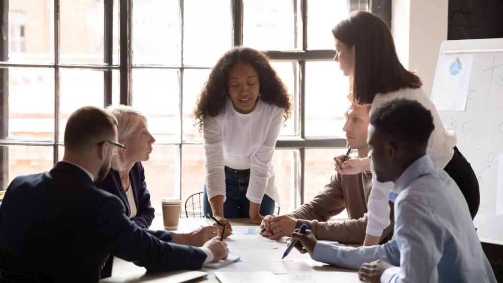 female professional leaning over table explaining marketing data analysis