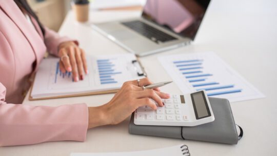 Woman using calculator with computer laptop, budgeting for PR