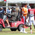 Buccaneers coach in a golf cart speaks to players including Antonio Brown