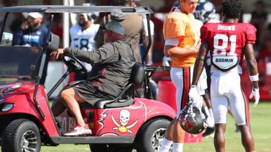 Buccaneers coach in a golf cart speaks to players including Antonio Brown