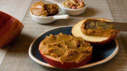 spreading peanut butter on an apple