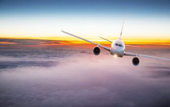 Commercial airplane jetliner flying above dramatic clouds in beautiful light. Travel concept.