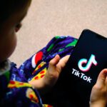 child holding a phone with tiktok app on screen