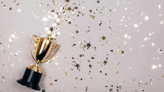 Sparkles grey background with a winners cup. Flat lay style.