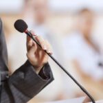 Businesswoman standing on stage and reporting for audience