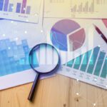 Magnifying glass and documents with analytics data lying on table,selective focus