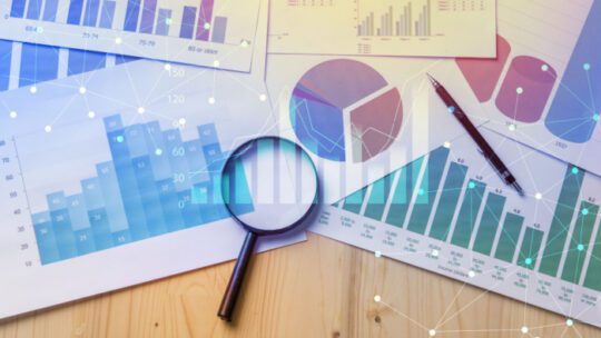 Magnifying glass and documents with analytics data lying on table,selective focus