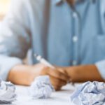 Close-up of crumpled paper on table with unhappy businesswoman was frustrated. Concept of no idea to thinking