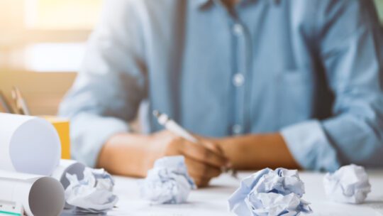 Close-up of crumpled paper on table with unhappy businesswoman was frustrated. Concept of no idea to thinking