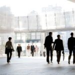 A group of people is against the backdrop of modern buildings. Blurred motion. Silhouette.