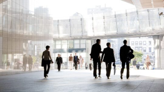 A group of people is against the backdrop of modern buildings. Blurred motion. Silhouette.