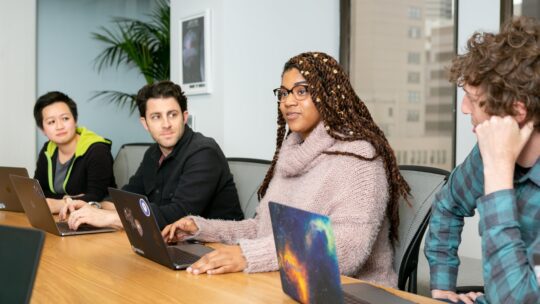 Professionals in a conference room, collaborating with laptops for productive meetings and teamwork.