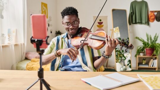 Blogger playing violin during online broadcast creating user generated content through a cell phone