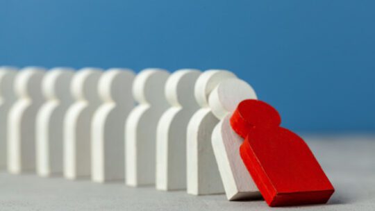 red person-shaped domino knocking down white dominoes in domino effect