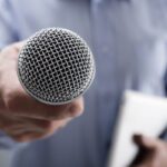 Hand holding a microphone conducting a business interview or press conference