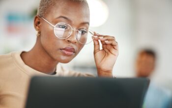 Office, computer and black woman with glasses, serious or reading email, news, online research or report.