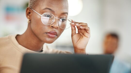 Office, computer and black woman with glasses, serious or reading email, news, online research or report.