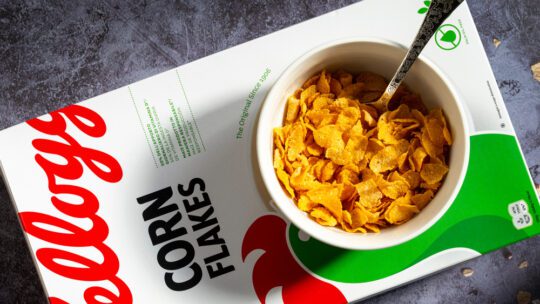 Top view of a Kellogg's Corn Flakes package, with a bowl being prepared from above