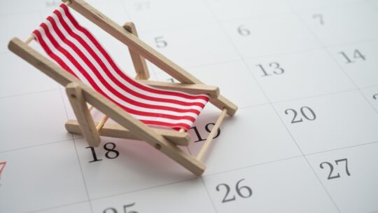 Red beach chair on white blank calendar background copy space. Annual leave travel period for relaxation concept. Period of paid time off (PTO) granted to employees by their employer.