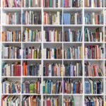 Modern library interior with white shelves full of countless books.