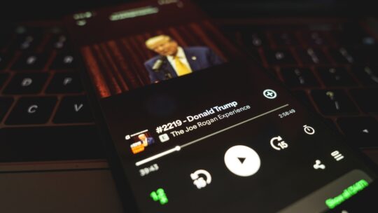 Joe Rogan experience on Spotify with Donald Trump as guest. Popular podcast displayed on phone screen