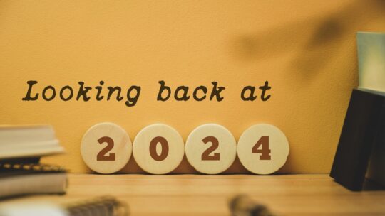 Looking back at the year 2024 concept on wooden chips and inscription. Best events of the year, highlights, review, performance, evaluation of 2024. Office desk background.
