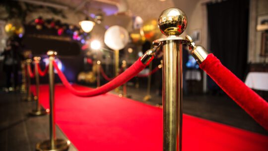 Red carpet between red velvet rope barriers showing a VIP walkway