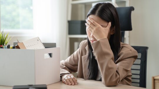 Close-up of young businessperson holding boxes of stuff after a job layoff