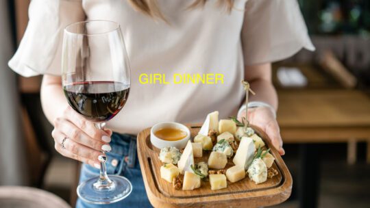GIRL DINNER example of a woman holding a wine and a plate of cheeses