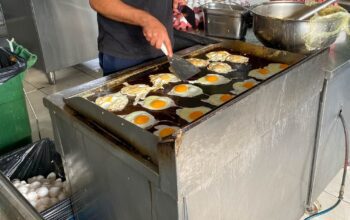 Chef, cook cooks a lot of eggs on a flat top stove