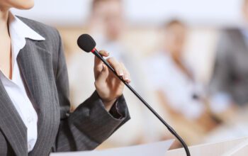 Businesswoman standing on stage and delivering a speech at a podium