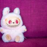 Laubu collectible figure from Pop Mart sitting on soft pink fabric background.